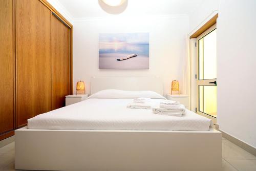 拉戈斯B90 - Casa Sardinha in Lagos的卧室配有白色的床和墙上的绘画作品