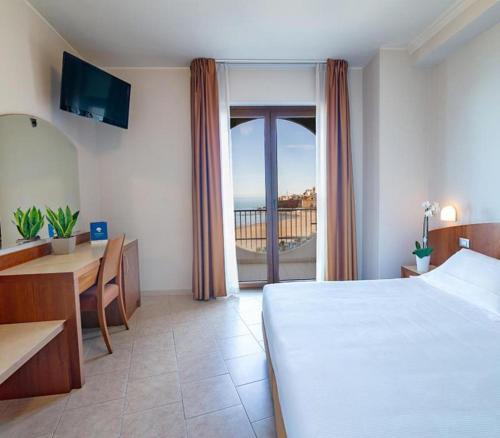 泰尔莫利梅里迪亚诺酒店的一间卧室配有一张床铺和一张桌子,并设有一个阳台