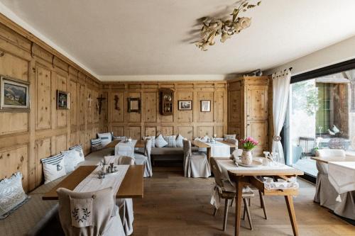 梅拉诺Bäcksteinerhof的餐厅设有木墙、桌子和吊灯。