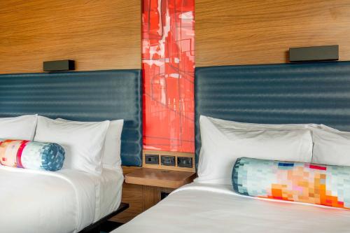 阿尔法利塔Aloft Alpharetta的两张睡床彼此相邻,位于一个房间里