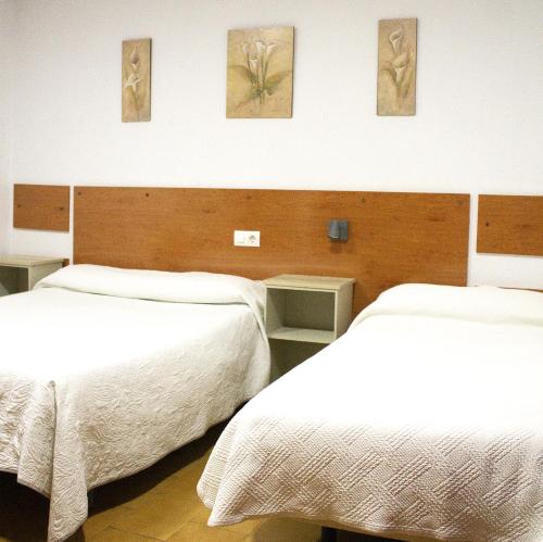 奇克拉纳－德拉弗龙特拉维拉别墅旅馆的配有白色床单的酒店客房内的两张床