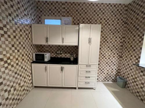 利雅德روعة بيتك306的厨房配有白色橱柜和微波炉