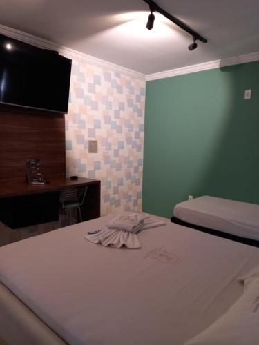 阿瓜斯克拉腊斯Hotel 1001 Prime Ade Águas Claras的客房设有两张床、一张桌子和一台电视。
