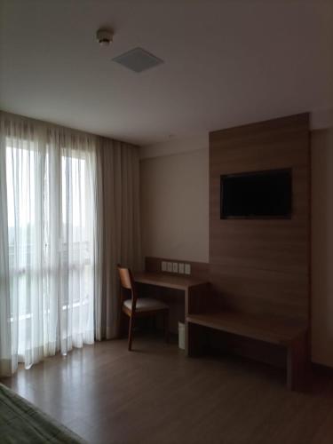 佩德拉阿祖尔Condomínio Vista Azul Hotel的酒店客房配有书桌和电视。