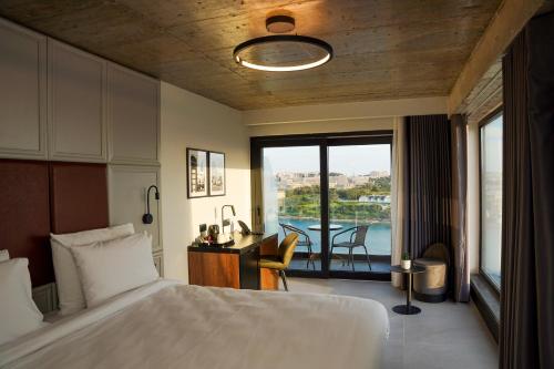 斯利马The Londoner Hotel Sliema的一间带一张床和一张书桌的卧室以及一个阳台
