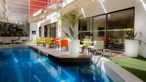 马拉喀什巴布酒店的一座带桌椅的游泳池位于酒店大楼旁
