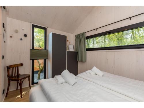 佐特兰德Tiny house on the edge of the forest in Zoutelande的一间卧室设有两张床、一把椅子和窗户。
