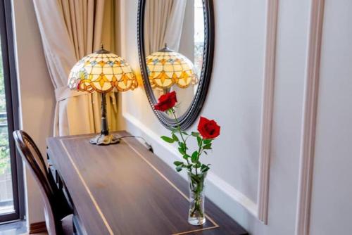 海防Sophia Hotel的一张桌子,上面有两盏灯和一个玫瑰花瓶