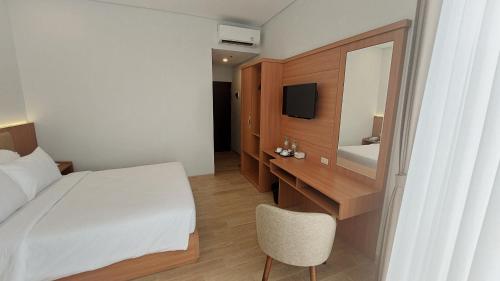泗水AYMAN SYARIAH HOTEL的一间卧室配有一张床、一张书桌和一面镜子