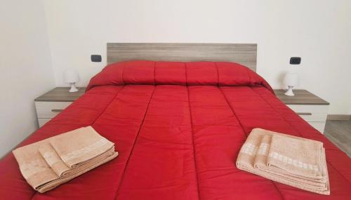 阿格拉泰布里亚恩扎LA PETITE MAISON的红色的床,上面有两条毛巾