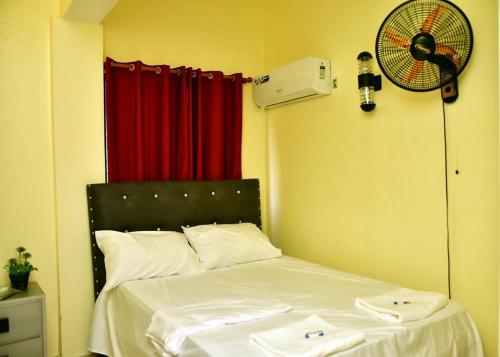 纳瓜Hotel Freedom Nagua的一间卧室配有一张带白色床单的床和风扇