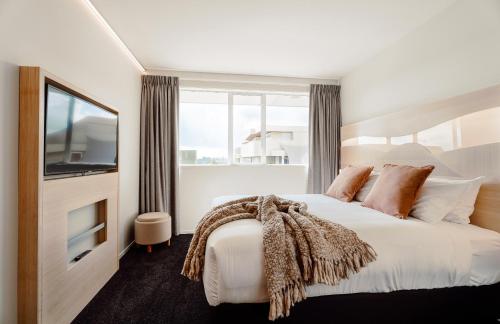 陶朗加CitySide Hotel Tauranga的一间卧室设有一张大床、电视和窗户。