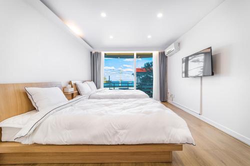 襄阳郡Sky Sea Pension的白色的卧室设有一张大床和一个窗户