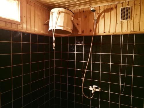 TüriKanarbiku tuba的带淋浴和风扇的黑色瓷砖浴室