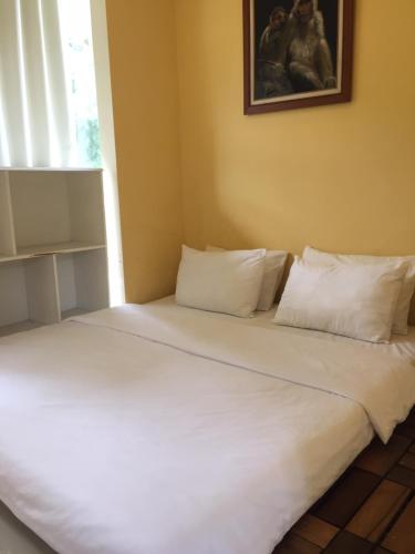 岩望House at Taman Dayu的一张带白色床单和枕头的床