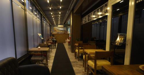 伊斯坦布尔Florya House Hotel的一间带桌椅和灯光的餐厅