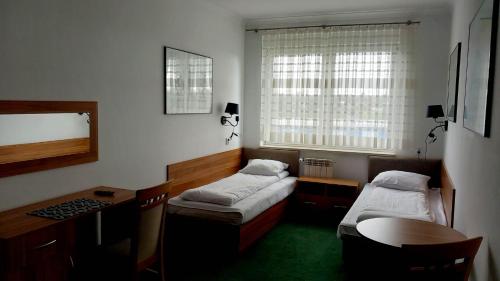 琴斯托霍瓦Hotel i Restauracja 13 Smaków的客房设有两张床、一张桌子和一张桌子。