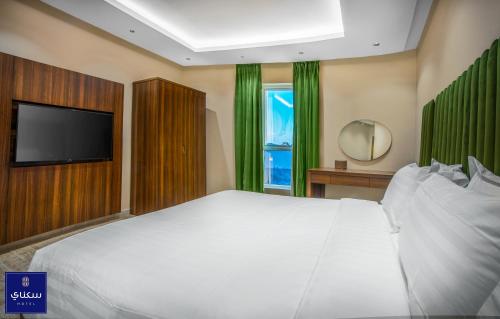 哈伊勒فندق سكناي الياسمين的卧室配有一张白色大床和一台平面电视。