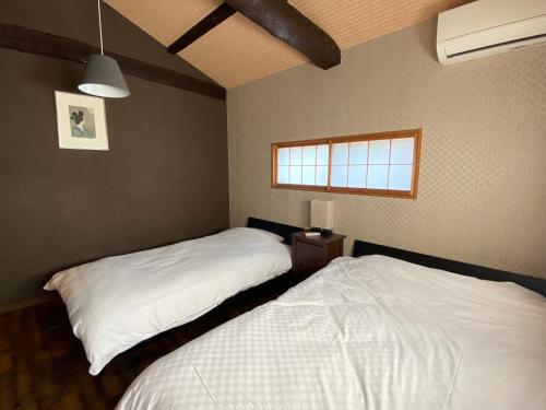 京都Samurai Suite 1 , 15mins from Kyoto Eki , 5 mins to Arashiyama的一间卧室设有两张床和窗户。