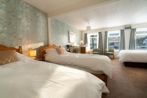 托伯莫里Harbour Guest House的酒店客房设有三张床和窗户。