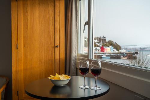 托伯莫里Harbour Guest House的一张桌子,上面放着两杯葡萄酒和一碗薯条