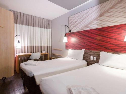 桑托斯ibis Santos Gonzaga Praia的酒店客房配有两张床和一张书桌