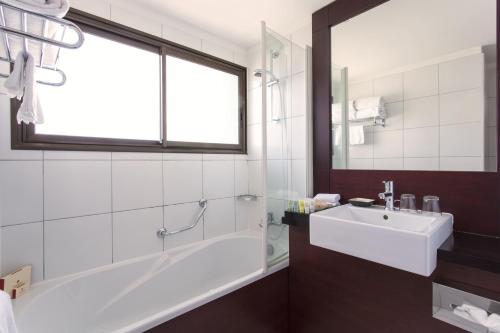 努美阿Ramada Hotel & Suites by Wyndham Noumea的带浴缸、水槽和窗户的浴室