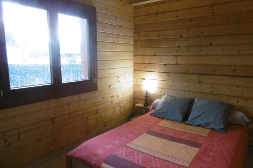 Saint-CômeChalet écologique en campagne bazadaise的木制客房内的一间卧室,配有一张床