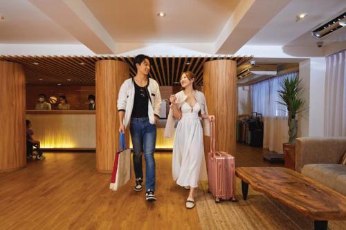曼谷Arck Hotel的两名妇女带着行李穿过酒店大堂