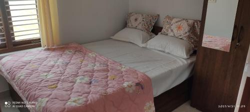 迈索尔Kailash Guest Home的一张带粉红色棉被和枕头的小床