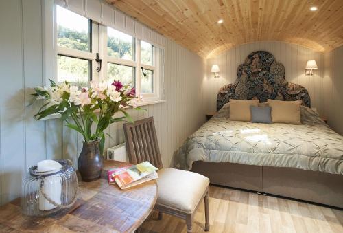 Anne's Hut Monmouthshire的一间卧室配有一张床和一张鲜花桌