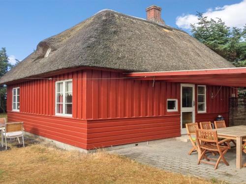 瓦伊厄斯斯特兰德Holiday Home Jorid - 300m from the sea in Western Jutland by Interhome的红色的房子,有茅草屋顶和桌子