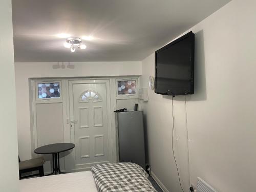 米尔顿凯恩斯Guest House in Milton Keynes的一间卧室配有一张床和一台平面电视
