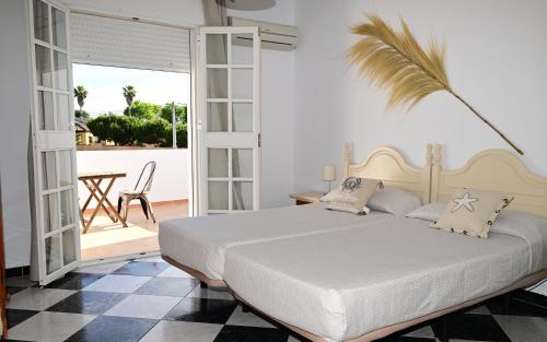 科尼尔-德拉弗龙特拉罗萨莱斯旅馆的卧室配有白色的床和棕榈树