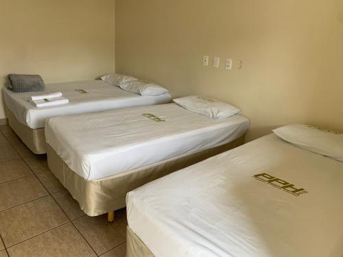 戈亚尼亚Pissin Plaza Hotel的配有白色床单的客房内的三张床