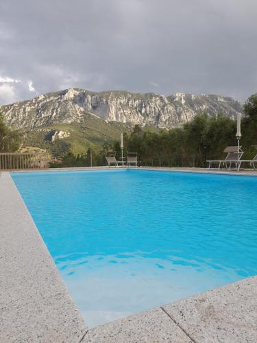 OnifaiAgriturismo Palas De Serra Country Resort的一座蓝色的游泳池,后面是一座山