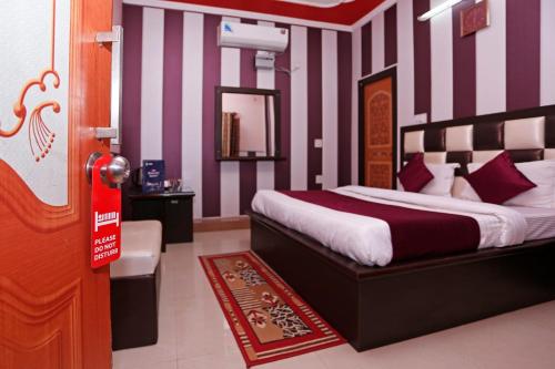 JwālāpurMehfil Hotel的一间卧室配有一张紫色和白色条纹的床