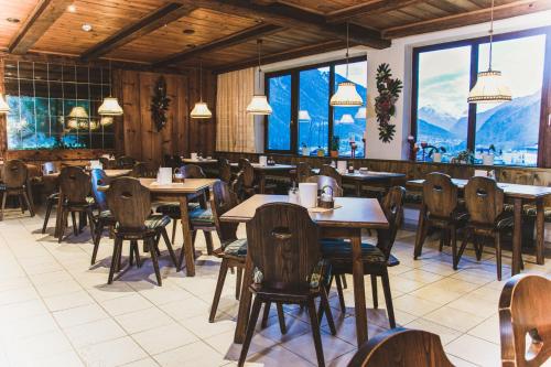 厄茨Hotel Marko的餐厅配有桌椅,位于山脉的背景中。