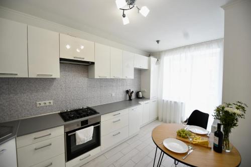捷尔诺波尔Cozy apartment next to the park的厨房配有白色橱柜和木桌