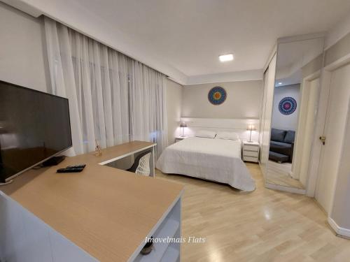 圣保罗Bienal Ibirapuera的一间卧室配有一张床和一张书桌及电视