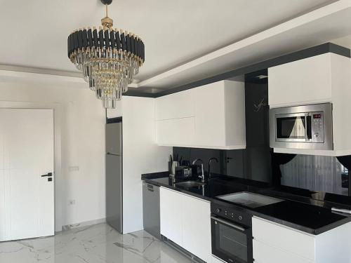 马赫姆拉Fully furnished 1+1 apartment in luxury complex Heaven Hills的厨房配有白色橱柜和吊灯。