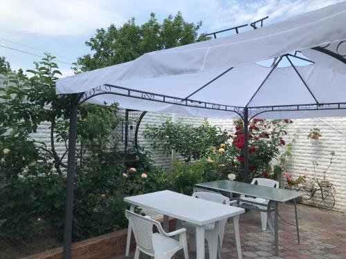 敖德萨Vilari Odessa的庭院内的白色遮阳伞,配有桌椅