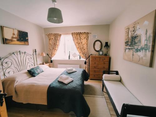 恩尼斯Tower View Lodge的一间卧室配有一张床、一张长凳和一个窗户。