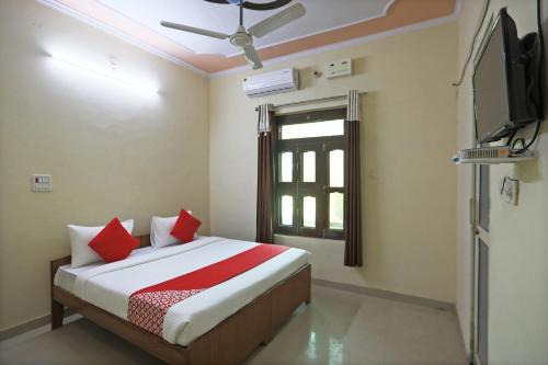 MahendragarhOYO 62761 Hotel Daksh的一间卧室配有一张带红色枕头的床和电视。