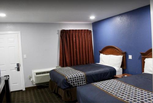 艾达Economy Inn的酒店客房设有两张床和蓝色的墙壁。
