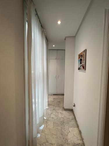 塞维利亚Iberflat Fabiola的走廊设有白色的墙壁和窗帘,铺有瓷砖地板。