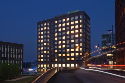 埃因霍温Holiday Inn - Eindhoven Airport, an IHG Hotel的城市街道上一座高大的建筑,有明亮的窗户