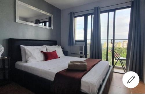 宿务Our oasis in Cebu City awaits you!的一间卧室设有一张床和一个享有美景的大窗户