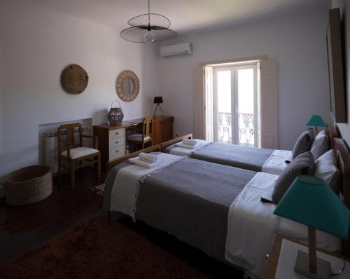 莱里亚Casa Da Palmeira的一间卧室设有两张床、一张桌子和一个窗口。