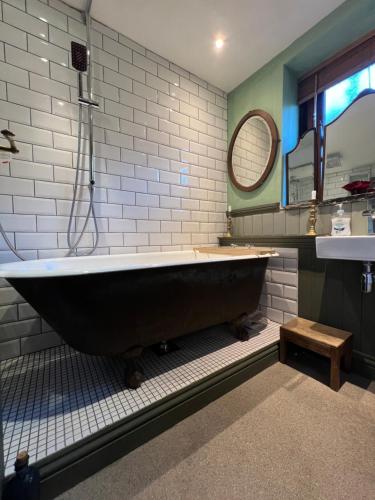 霍姆弗斯The Writers Cottage - Intriguing & Romantic的浴室设有大型黑色浴缸,配有镜子